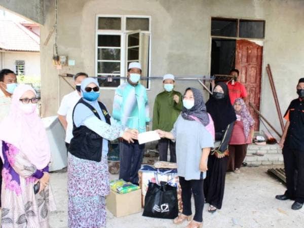 Wan Haslinda (kanan) menerima bantuan segera daripada Mumtaz (kiri) di rumahnya di Kampung Dara Main, Perupok, Bachok pada Khamis.