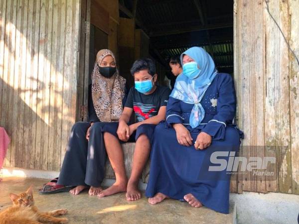 Mek Zah (kanan) bersama dua anaknya di rumah mereka di Kampung Sering, Kedai Lalat, Kota Bharu.