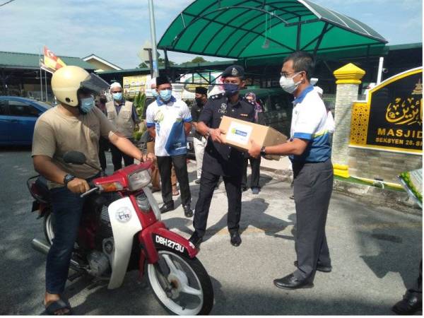 Saipolyazan (kanan) bersama Mohammad Firdaus (dua dari kanan) menyerahkan sumbangan kepada salah seorang penerima dalam satu majlis ringkas di Masjid Al Faizin, Seksyen 28, Shah Alam pada Jumaat.