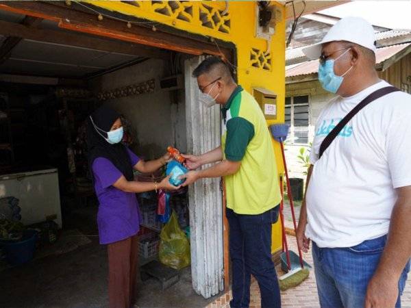 Mohd Jazri (tengah) menyerahkan daging korban kepada seorang penduduk Pulau Perhentian.