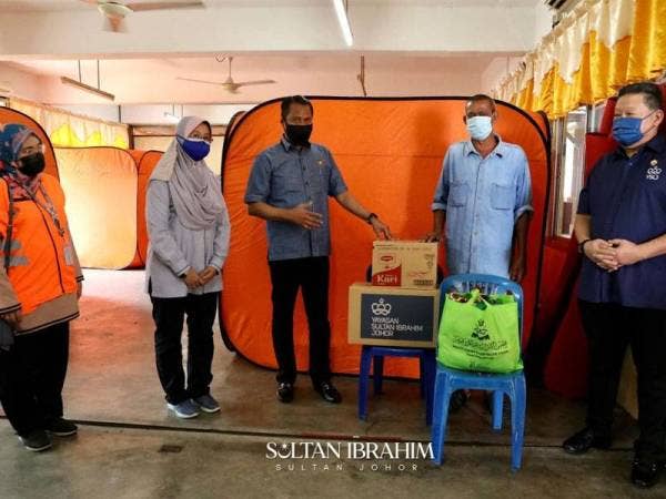 David Wong (kanan) menyampaikan bantuan Sultan Johor kepada mangsa ribut di PPS Sekolah Kebangsaan Seri Setia Jaya, Tanjung Sedili, Kota Tinggi pada Sabtu.