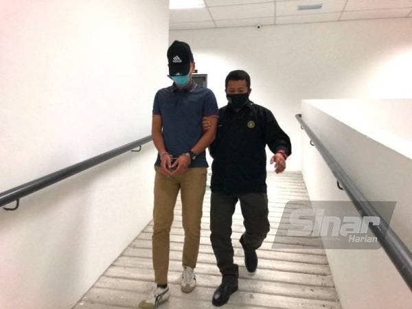 Tertuduh (kiri) dibawa anggota SPRM keluar dari bilik Mahkamah Sesyen di Kota Bharu pada Selasa.