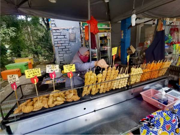 Nurul Aini menyusun makanan yang dijual di gerai ibu bapanya di Hutan Rekreasi Ulu Bendul, Kuala Pilah.