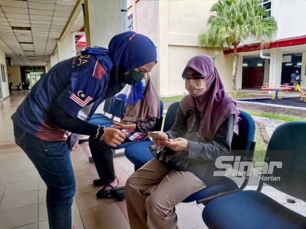 Norbaizura memeriksa MySejahtera seorang penerima vaksin.