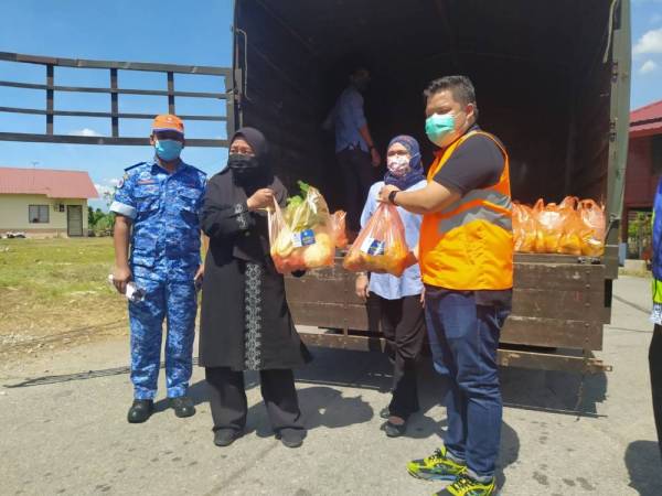 Wan Norashikin (dua dari kiri) menyerahkan bantuan barang basah yang akan diagihkan kepada penduduk di empat lokaliti PKPD di dalam kawasan DUN Kampung Gajah pada Sabtu.