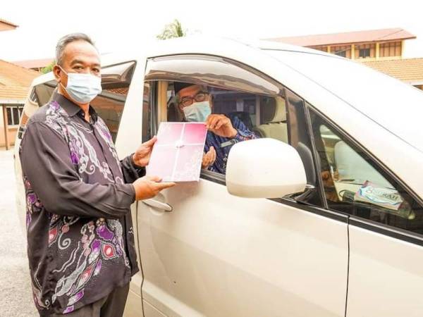 Mohd Razali (kiri) menyampaikan APC 2020 kepada salah seorang guru cemerlang secara padu lalu diperkarangan pejabat PPD Pekan. - Foto ihsan PPD Pekan