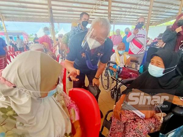 Annuar (tengah) beramah mesra dengan warga emas yang menunggu giliran semasa Program Vaksinasi Peringkat Parlimen Ketereh di Kompleks Yayasan Kemiskinan (YKK), Kota Bharu pada Ahad.