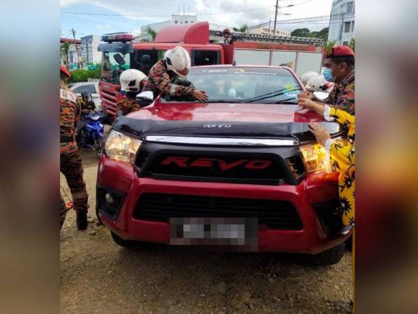 Anggota bomba menjalankan operasi membuka pintu dan mengeluarkan mangsa yang sedang nyenyak tidur dalam pacuan empat roda Toyota Hilux. - Foto ihsan Bomba Perak