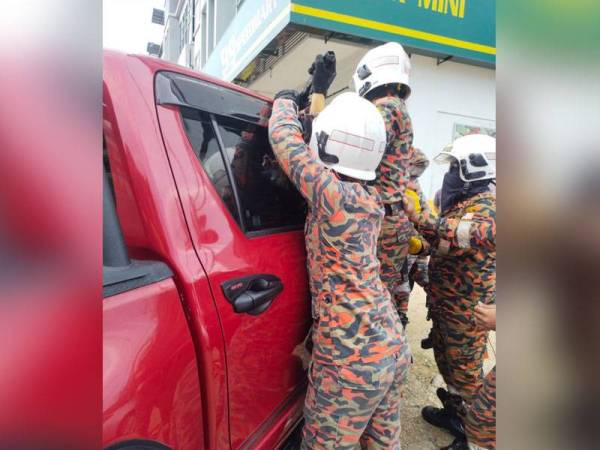 Anggota bomba berusaha membuka pintu kenderaan menggunakan peralatan khas untuk mengeluarkan mangsa. - Foto ihsan Bomba Perak