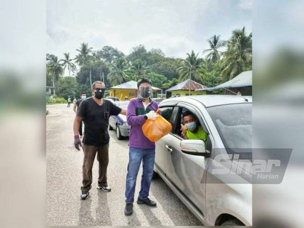 Roslan mengagihkan durian secara pandu lalu kepada penduduk.