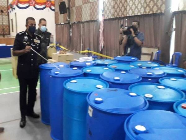 Ayob Khan (dua kiri) menunjukkan tong biru cecair pati arak yang dirampas melibatkan nilai RM2.1 juta, selepas sidang akhbar di IPK Johor, Johor Bahru, pada Selasa.