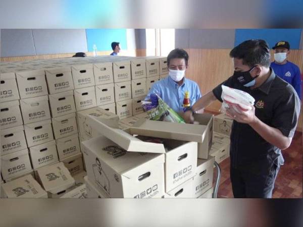 Mohd Shahar (kanan) memeriksa bakul makanan sebelum dihantar kepada penduduk di kawasan PKPD Parlimen Paya Besar pada Rabu.