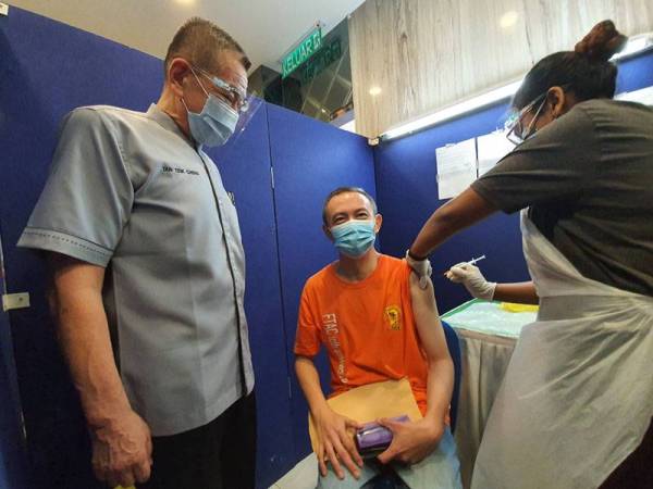 Teik Cheng melihat proses suntikan vaksinasi yang dilakukan.