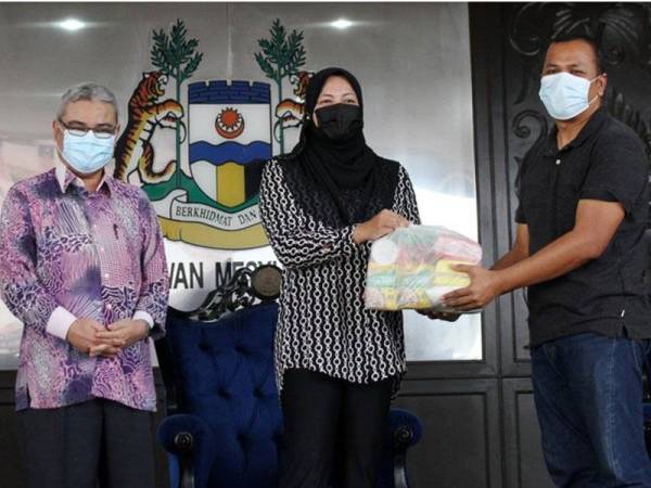 Nolee Ashilin (tengah) menyampaikan sumbangan bakul makanan kepada wakil peniaga Memory Lane, Ku Ahmad Ku Jusoh (kanan) di Majlis Bandaraya Ipoh pada Khamis. - Foto Bernama
