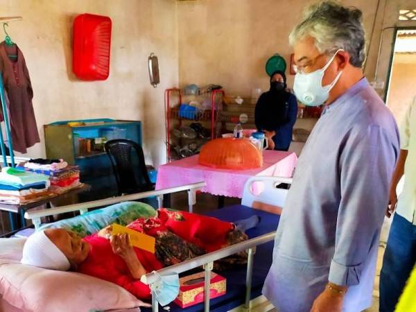 Seri Paduka Baginda menyantuni salah seorang warga emas dalam lawatan selama dua jam di Rompin pada Khamis. - Foto Istana Negara