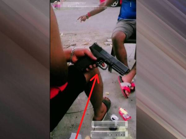 Tangkap layar rakaman video yang memperlihatkan tiga lelaki dengan seorang daripada mereka memegang senjata menyerupai sepucuk pistol.