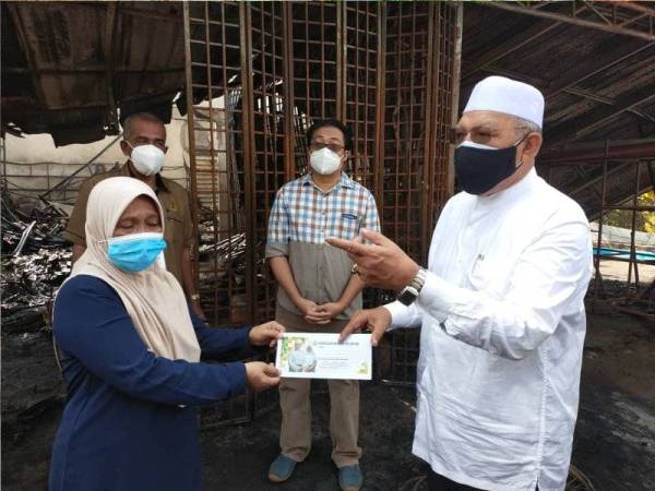 Ahmad (kanan) turun padang menyampaikan sumbangan awal berjumlah RM2,000 dari Tabung Serambi Mekah kepada Roslina di Kampung Gerong, Tumpat pada Sabtu.