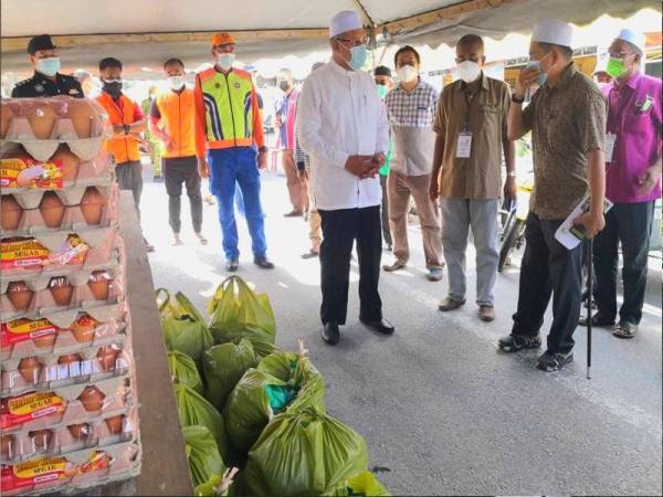 Ahmad (kiri, di hadapan) mengadakan lawatan dan penyerahan sumbangan bakul makanan kepada penduduk di PKPD Kebakat, Tumpat pada Sabtu.