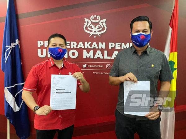 Noor Hariri (kiri) dan Tengku Haphiz menunjukkan laporan polis yang dibuat terhadap Muhyiddin pada sidang akhbar di Pusat Dagangan Dunia Kuala Lumpur (WTCKL) pada Sabtu.