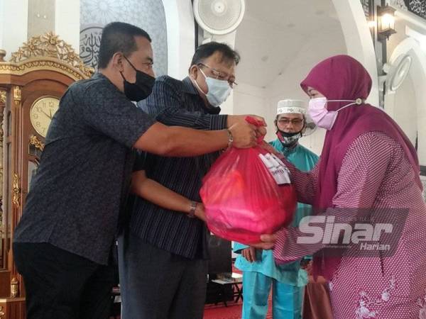 Eddin Syazlee (dua dari kiri) menyerahkan bantuan bakul makanan Pemulih kepada penerima di Masjid Senaling, Kuala PIlah pada Sabtu.