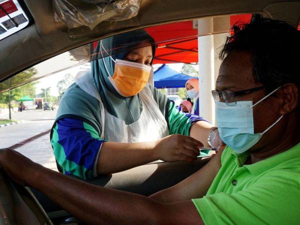 Jururawat dari Pejabat Kesihatan Daerah Pendang melakukan suntikan vaksin kepada penerima vaksin pada aktiviti pemberian vaksin pandu lalu di taman permainan dan rekreasi Pendang, hari ini.