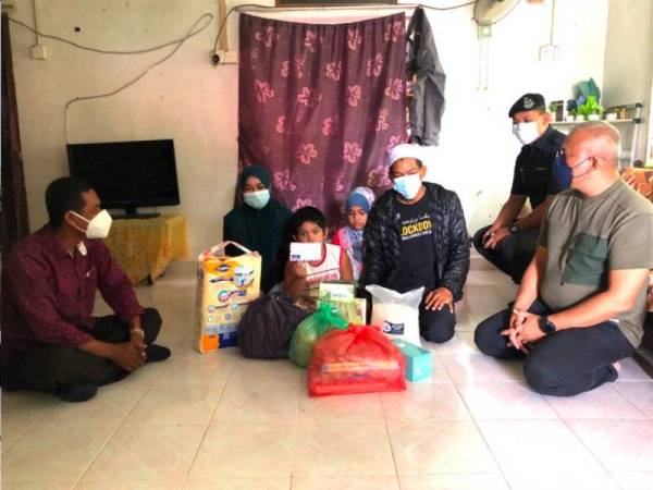 Abd Halim (kanan) hadir menyampaikan sumbangan makanan dan telefon bimbit kepada keluarga pesakit buah pinggang kronik, Mohd Faizal (tiga dari kanan) di Kampung Pasir Pekan Hilir, Tumpat pada Isnin. - FOTO SINAR HARIAN