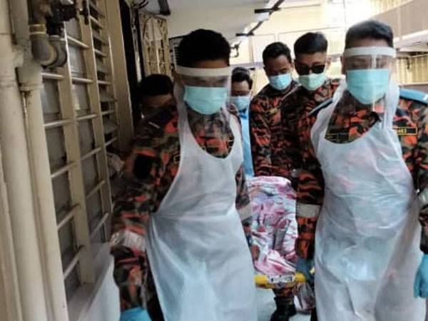 Anggota bomba mengeluarkan mangsa di rumahnya di Taman Pakatan Bercham, Ipoh pada Isnin.