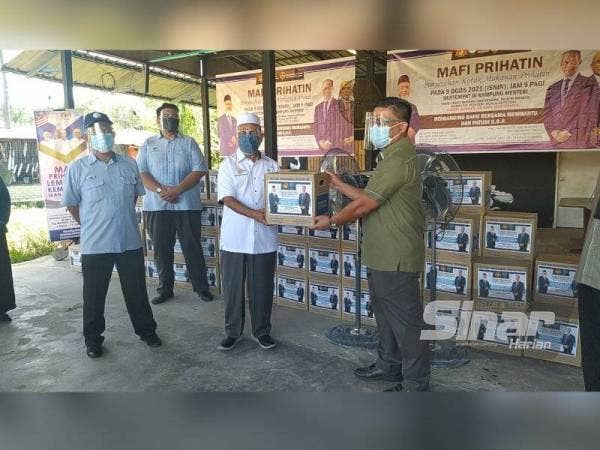 Syed Abu Hussin Hafiz (dua dari kanan) menyerahkan bakul makanan secara simbolik kepada Mohamed Akmal pada Program Penyerahan Kotak Makanan MAFI di Kampung Menteri, Kuala Sepetang, Taiping pada Isnin.
