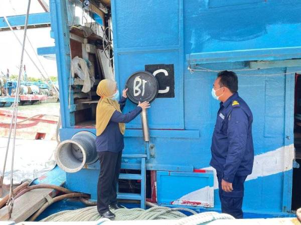 Noraisyah bersama pegawainya menunjukkan kod palsu yang digunakan empat nelayan pada bot mereka bagi mengaburi mata pihak berkuasa.