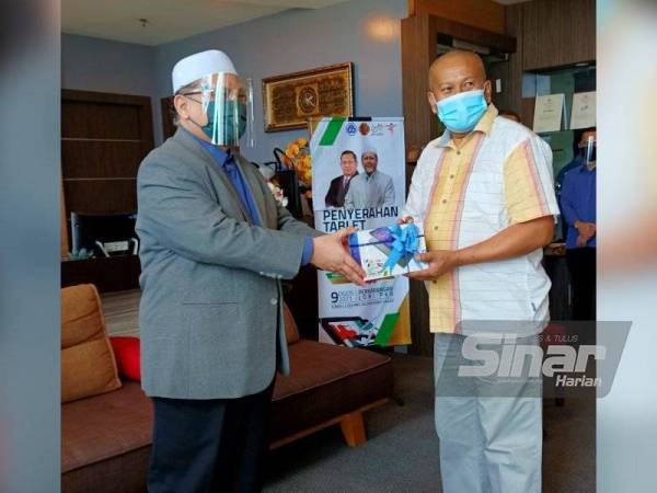 Mohd Amar (kiri) menyampaikan sumbangan peranti pintar kepada anak-anak pelanggan A-Rahn untuk kegunaan PdPR di Ibu Pejabat Permodalan Kelantan Berhad (PKB), Kota Bharu pada Isnin.