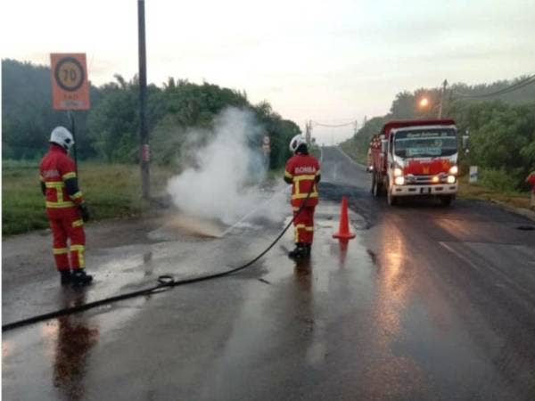 Anggota bomba membantu memadamkan kebakaran sebuah kereta yang terlibat dalam kemalangan akibat tumpahan minyak di KM15, Jalan Felda Mempaga-Chinta Manis, pada pagi Isnin.
