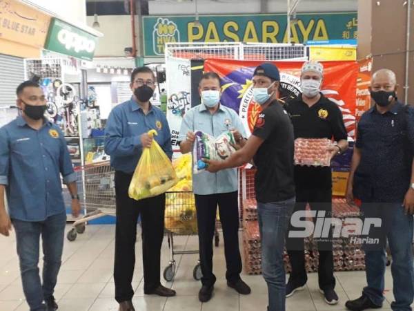 Che Zakaria (tiga dari kiri) disaksikan Maharam (dua kanan) dan Zamrin (kanan) menyerahkan bakul makanan kepada wakil MaSia di Kip Mart Masai, Pasir Gudang, pada Selasa.