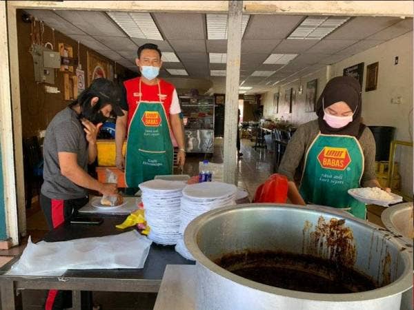 Azhar (dua dari kanan) melihat dua pekerjanya membungkus makanan untuk tempahan pelanggan di restorannya di Kota Bharu pada Selasa.