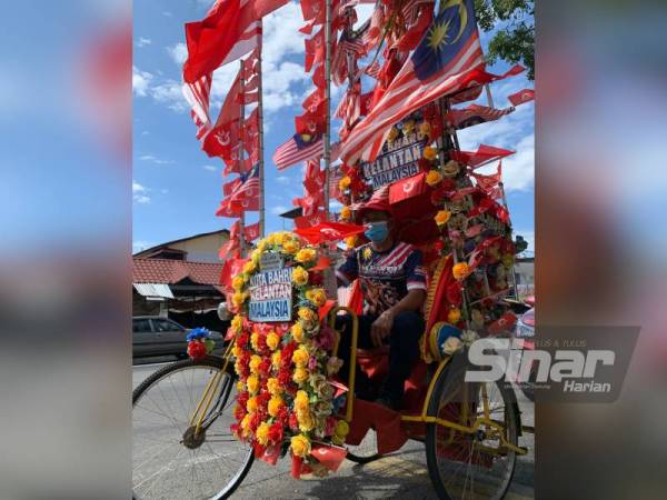 Che Kamarudin membetulkan bendera yang digantung di beca miliknya.