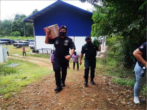 Mazli (kiri) bersama Sahimi (kanan) masing-masing memikul kotak berisi barang makanan dan beras untuk penduduk di Kampung Lahanas Siba dalam Program Op Bantu di Kota Belud.