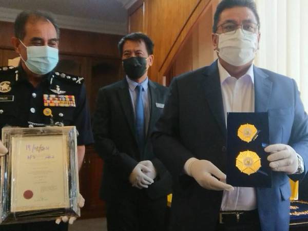 Sulaiman (kanan) menunjukkan pingat palsu selepas sidang akhbar di Pejabat Ketua Menteri, di Seri Negeri, Ayer Keroh, Melaka pada Rabu.