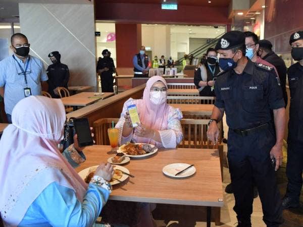 Rohaimi (kanan) membuat pemeriksaan bagi memastikan pelanggan di salah sebuah restoran pada Rabu mendapat suntikan penuh dua dos vaksin iaitu antara syarat SOP baharu dine-in.