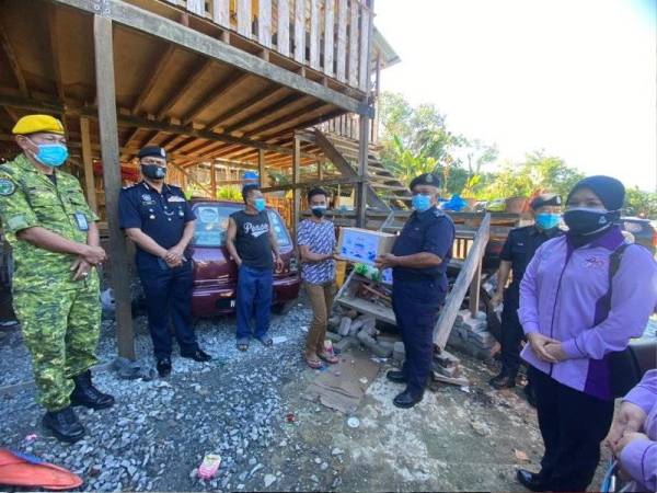 Yusuh (dua dari kanan) menyampaikan bakul makanan dalam program Op Bantu Fasa 3 IPD Kota Kinabalu di sekitar Kota Kinabalu.