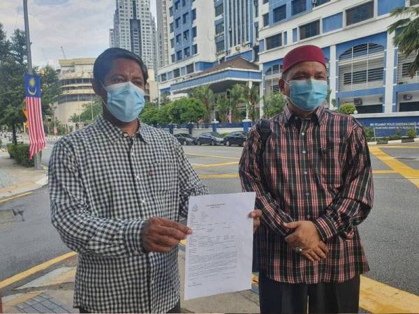 Mohd Zai (kiri) menunjukkan laporan yang dibuat di Ibu Pejabat Polis Daerah (IPD) Dang Wangi, Kuala Lumpur pada Khamis.