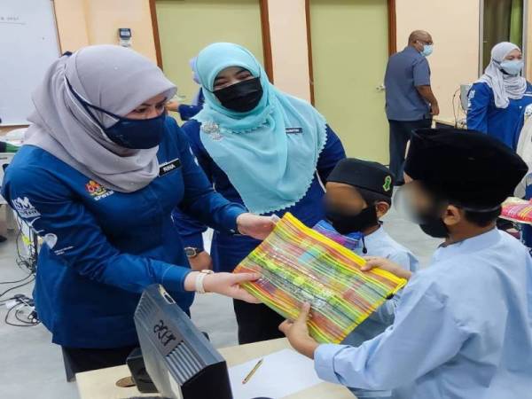 Rina (kiri) menyampaikan cenderahati kepada penghuni Rumah Kanak-Kanak Pokok Sena selepas meninjau pusat perlindungan tersebut pada Jumaat. Hadir sama Halimaton Shaadiah.