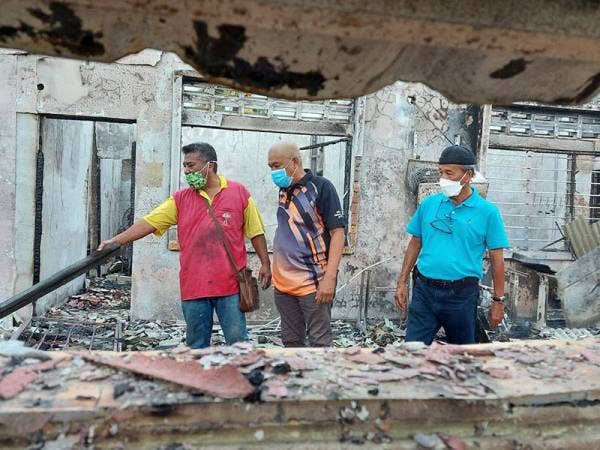 Mohd Elan (kiri) memeriksa rumahnya yang musnah dalam kebakaran di Manjoi pada Jumaat.