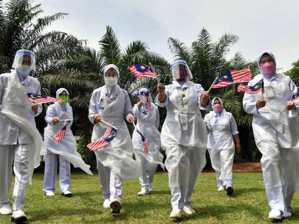 Petugas barisan hadapan Anisah Mohd Radzali (tiga, kiri) bersama rakan-rakan mengibarkan Jalur Gemilang sempena sambutan Hari Kebangsaan ke-64 yang akan disambut pada 31 Ogos ini ketika ditemui pada program vaksinasi di Sekolah Kebangsaan Tanggol hari ini. - Foto Bernama