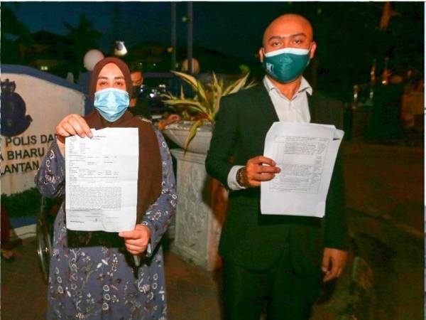 Rozita (kiri) dan peguamnya, Muhammad Hariz menunjukkan laporan polis dan surat saman ke atas empat individu terbabit di Ibu Pejabat Polis Daerah (IPD) Kota Bharu.