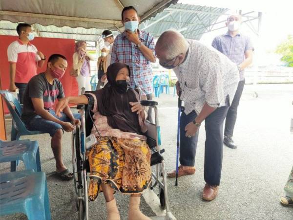 Mahfuz (kanan) beramah mesra dengan seorang warga emas yang menerima suntikan vaksin di PPV sementara Masjid Bukit Pinang di sini pada Isnin.