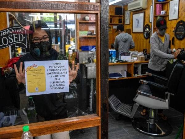 Dua orang pekerja Kedai Gunting Rambut Stable Barbershop Amir Putra (kanan) dan Nola Ebitry (kiri) membersihkan kedai sebagai persediaan memulakan semula operasi perniagaannya esok. - Foto Bernama