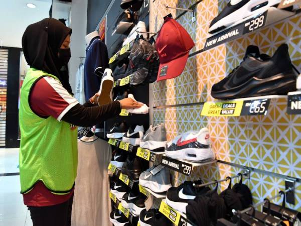 Para petugas sebuah kedai peralatan sukan membuat persiapan untuk pembukaan semula kedai. - Foto Bernama