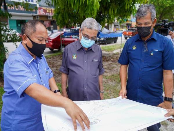 Rumaizi (tengah) ketika melihat pelan projek infrastruktur yang sedang dalam pembinaan di sekitar Ipoh pada Rabu. - Foto MBI