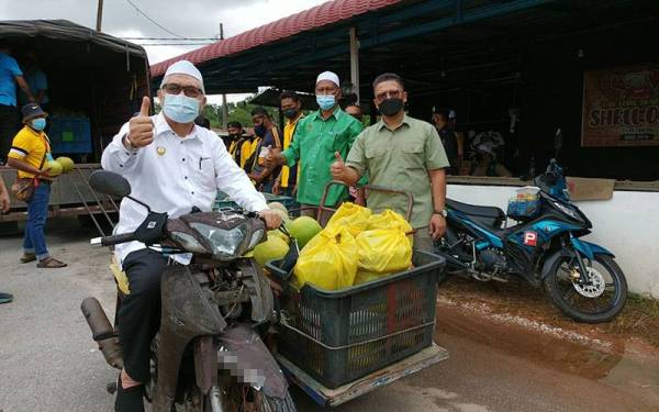 Razman (kiri) bersama bungkusan buah-buahan tempatan yang akan diagihkan kepada penduduk di PKPD Kampung Menteri, Kuala Sepetang.