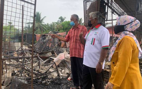 Mohd Adhan (tengah) melihat kedai-kedai yang terlibat dalam kebakaran pada Selasa lalu.