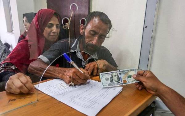 Penduduk Palestin menerima bantuan wang tunai disalurkan Qatar di sebuah pejabat pos di bandar Gaza. - Foto: Agensi
